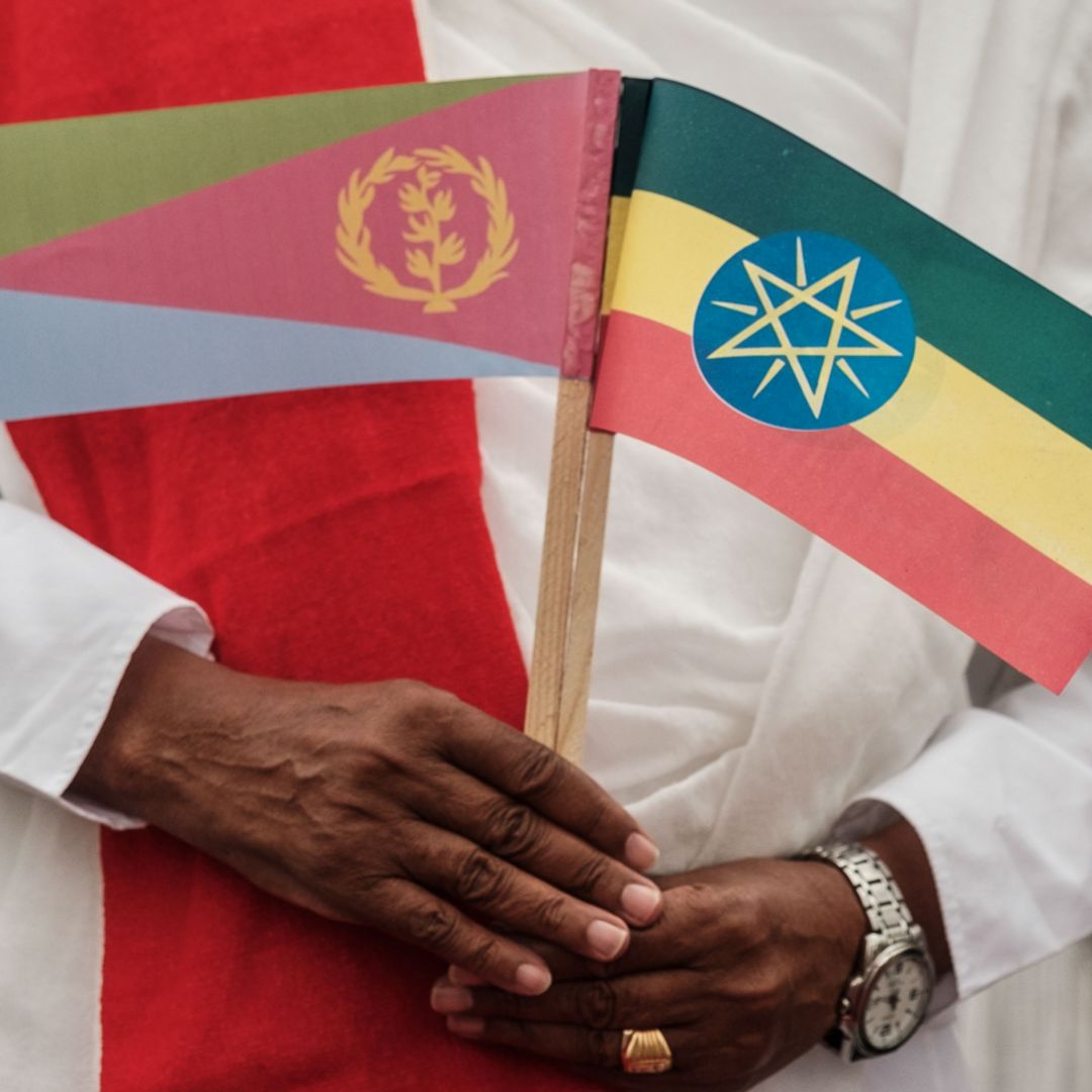 A man holds the flags of Eritrea, left, and Ethiopia as he waits for the arrival of Eritrea's president at an airport in Gondar, northern Ethiopia, on Nov. 9, 2018.