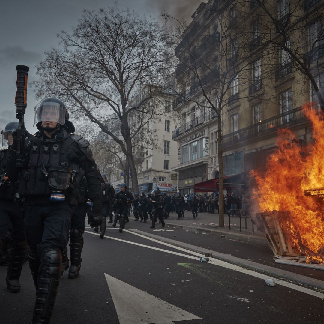 Riot police walk past a street fire during violent clashes over the government's reform of the pension system March 23, 2023, in Paris. As protests against French President Emmanuel Macron's decision to approve a controversial pensions reform without a vote in the National Assembly continue, the country's main trade unions will hold a general strike March 28. Riot police walk past a street fire during violent clashes over the government's reform of the pension system March 23, 2023, in Paris.