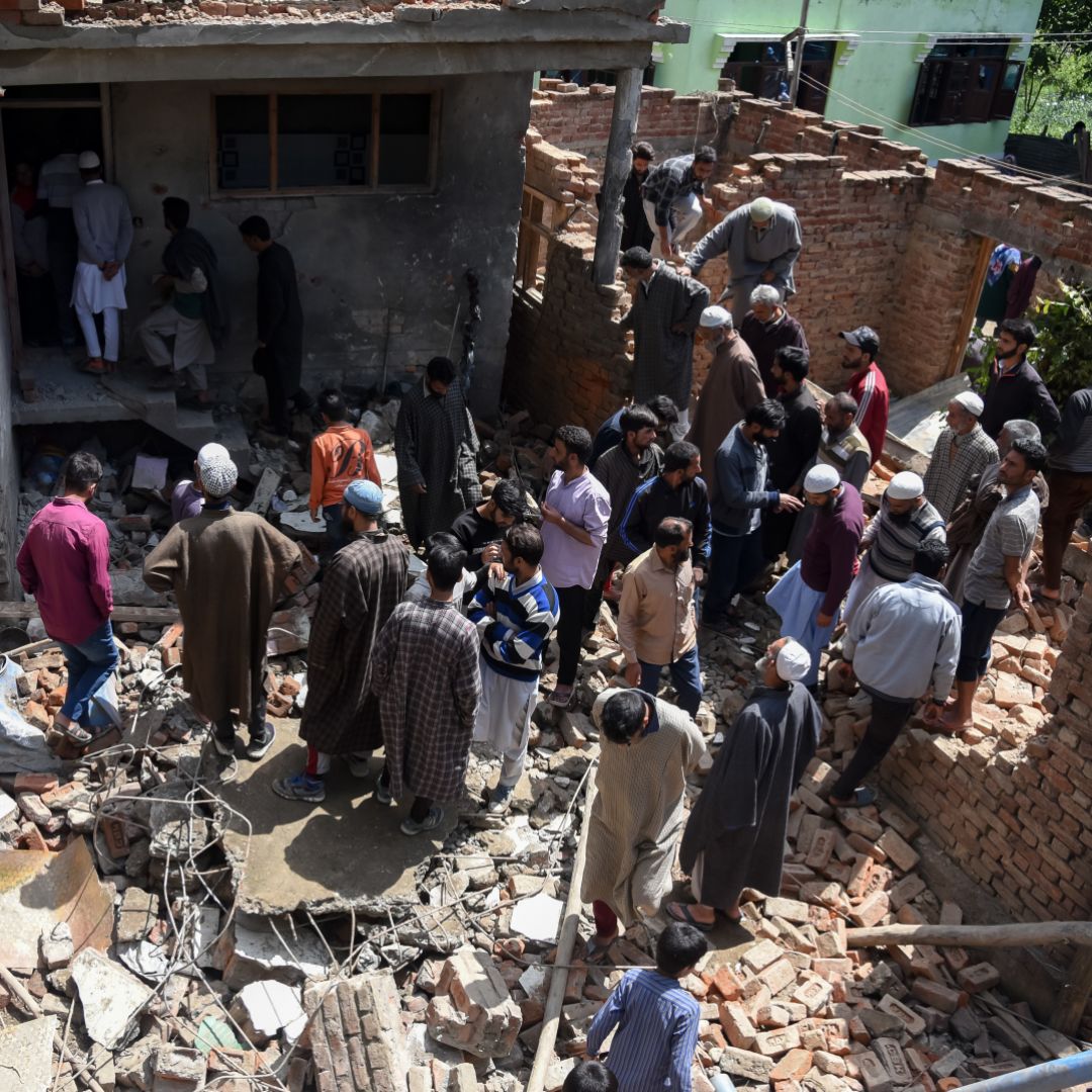 Kashmiri villagers gather around a partially damaged house after a gunfight in Pulwama, South of Srinagar, on May 18, 2019, after four rebels died in two separate clashes.