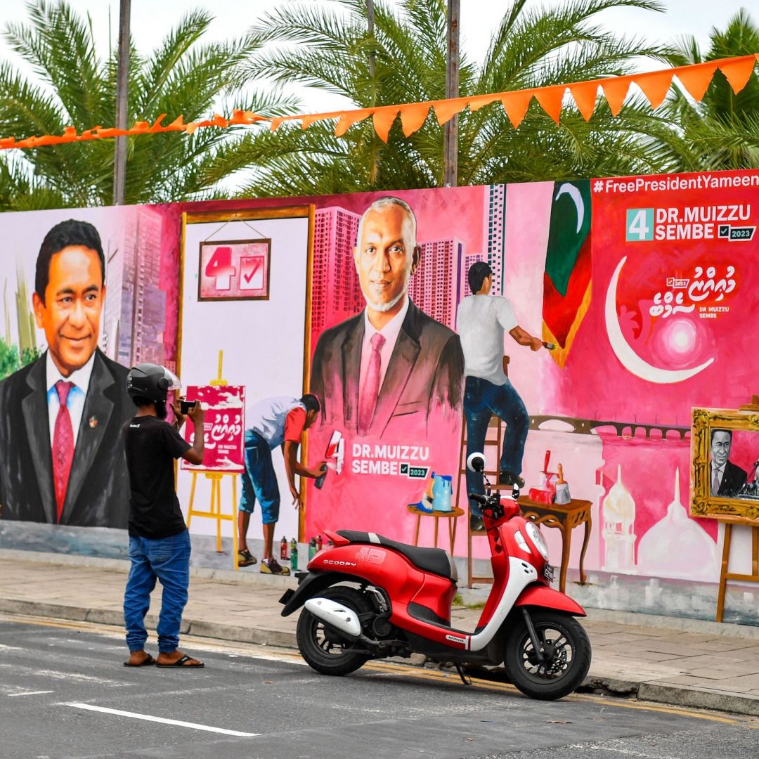  A commuter in Male, the Maldives, takes pictures of a decorated wall along a street ahead of the country's presidential election on Sept. 6, 2023.