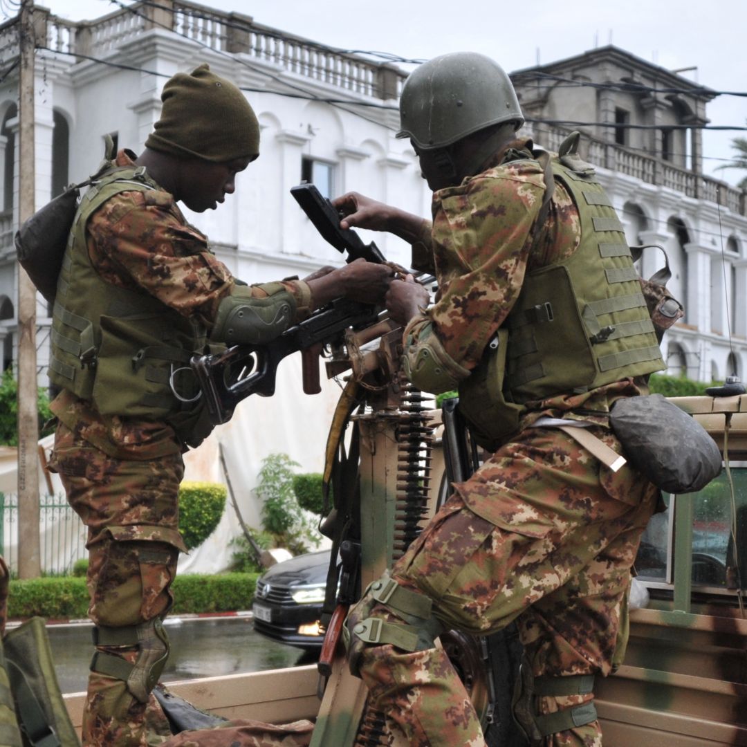 Malian soldiers outside the presidential palace in Bamako service the weapon on a military vehicle. 