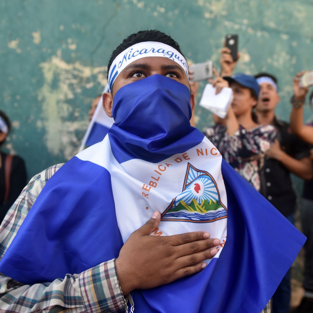 In this photograph, demonstrators sing the Nicaraguan national anthem in front of a police station during a protest against President Daniel Ortega's government in Managua on April 25.