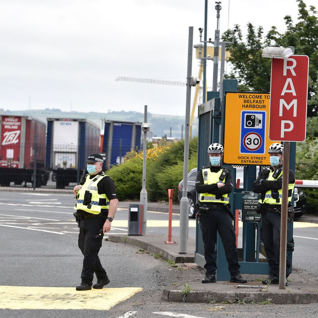 Police officers watch protesters rally against the Northern Ireland protocol in Belfast on July 3, 2021. 