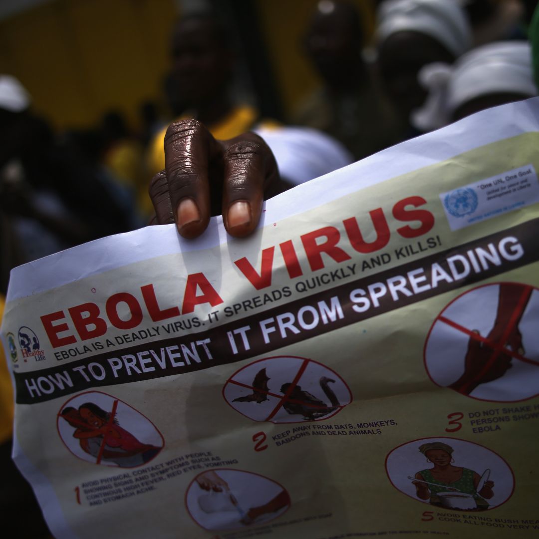 A person holds up a flyer for an event on Ebola awareness.