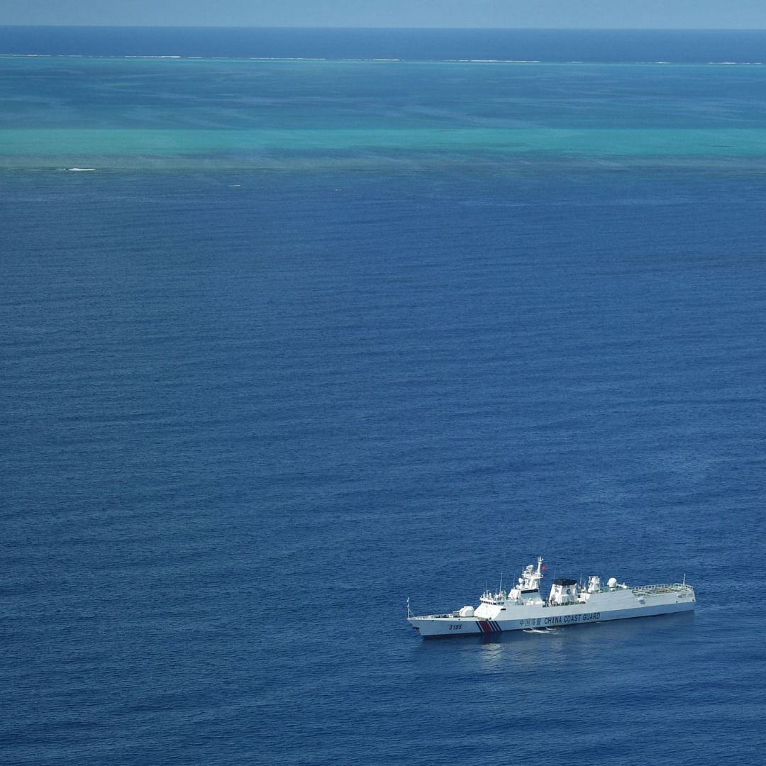 A photo taken during a Philippine surveillance flight on Sept. 28, 2023, shows a Chinese coast guard ship on patrol near the Scarborough Shoal (seen in the background) in the South China Sea.