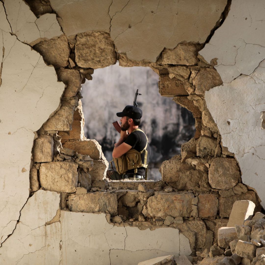A fighter of the Turkish-backed Syrian National Army is seen through the hole of a damaged building in the northern town of Marea, facing the Kurdish-controlled area of Tal Rifaat, on Aug. 2, 2022. A fighter of the Turkish-backed Syrian National Army is seen through the hole of a damaged building in the northern town of Marea, facing the Kurdish-controlled area of Tal Rifaat, on Aug. 2, 2022.