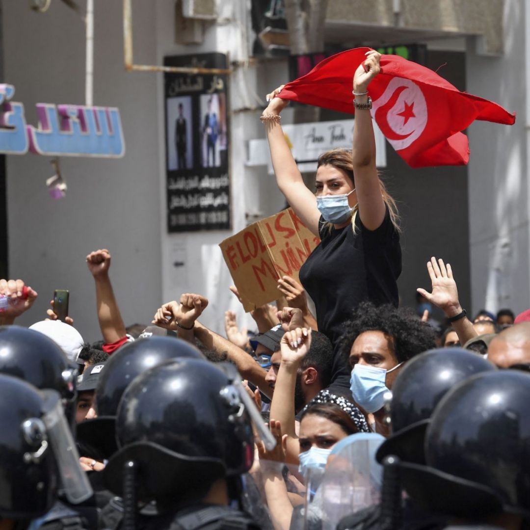 A protester lifts a Tunisian flag at an anti-government rally in Tunis on July 25, 2021.