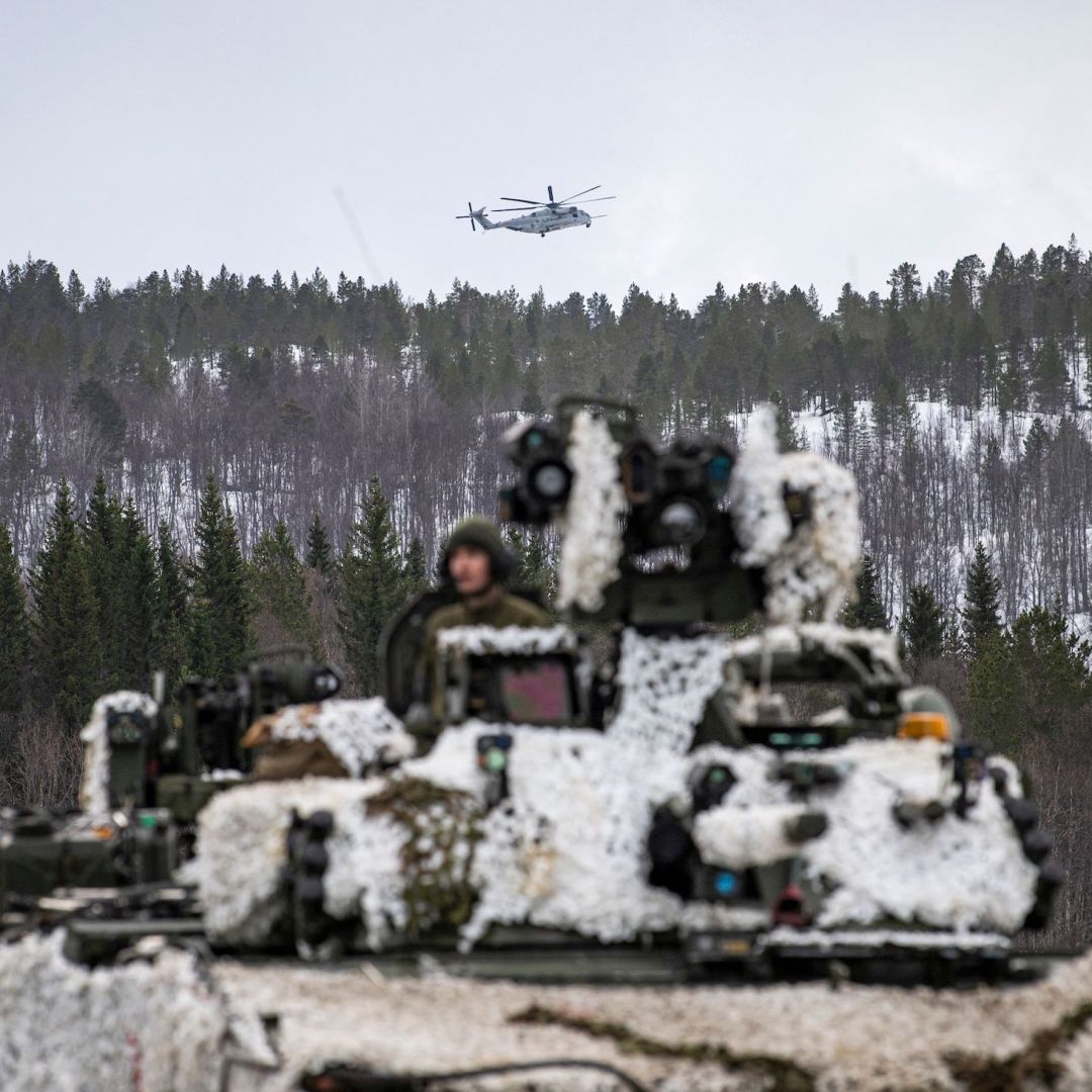 A heavy-lift helicopter operated by the U.S. military flies over a tank in Setermoen, Norway, during a military exercise involving NATO troops and partner countries on March 22, 2022. 