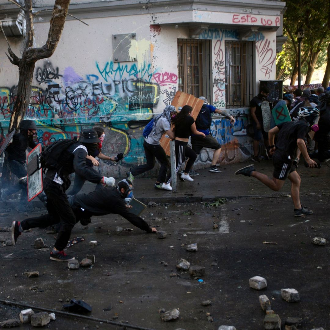 Protesters in Santiago, Chile, run from riot police on Nov. 19, 2019. Mass protests are happening in a growing number of countries for different reasons and with different goals. This photo shows protesters in Santiago, Chile, running from riot police on Nov. 19, 2019.