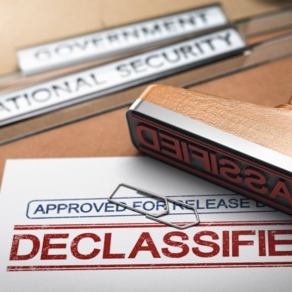 3D illustration of two folders and a rubber stamp with the word "declassified" printed on a document.