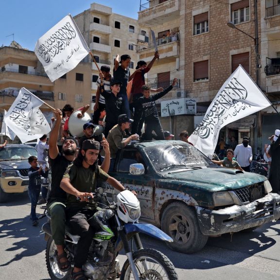 Members of Syria's top jihadist group, the al Quada-linked Hayat Tahrir al-Sham, parade through the city of Idlib on Aug. 20, 2021, in celebration of the Taliban's takeover of Afghanistan.