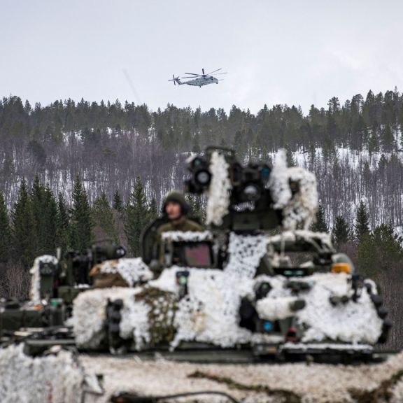 A heavy-lift helicopter operated by the U.S. military flies over a tank in Setermoen, Norway, during a military exercise involving NATO troops and partner countries on March 22, 2022. 
