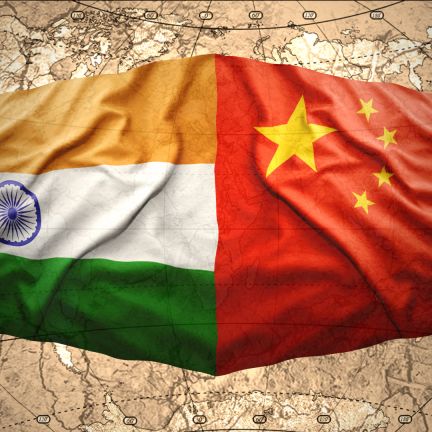 An image depicts waving Chinese and Indian flags overlaying a map of the world. An image depicts waving Chinese and Indian flags overlaying a map of the world.
