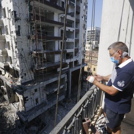 A man looks from the balcony of a building, damaged by the port explosion a day earlier, in Beirut, Lebanon on Aug. 5, 2020. A man looks from the balcony of a building, damaged by the port explosion a day earlier, in Beirut, Lebanon on Aug. 5, 2020.