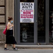 A woman wearing a face mask walks past a closed shop in Rome, Italy, on May 18, 2020. The sign on the store window reads "Without government aid, we cannot reopen on May 18. Thousands of employees at risk." A woman wearing a face mask walks past a closed shop in Rome, Italy, on May 18, 2020. The sign on the store window reads "Without government aid, we cannot reopen on May 18. Thousands of employees at risk."