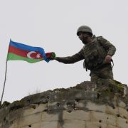 An Azeri soldier attaches Azerbaijan’s national flag to a tower near a town in Nagorno-Karabakh on Nov. 26, 2020. 