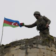 An Azeri soldier attaches Azerbaijan’s national flag to a tower near a town in Nagorno-Karabakh on Nov. 26, 2020. An Azeri soldier attaches Azerbaijan’s national flag to a tower near a town in Nagorno-Karabakh on Nov. 26, 2020.