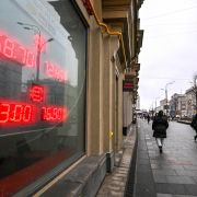 Pedestrians walk past a board at a currency exchange office in Moscow, Russia, on Jan. 16, 2023. 