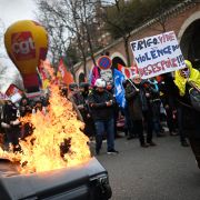 A protestor holds a placard that reads ''Empty Fridge Equals Violence of Dispair'' near a pile of burning trash during a demonstration in Paris, France, against the government's proposed pension reform on March 11, 2023. 