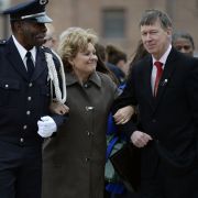Lisa Clements (C), wife of fallen Department of Correction executive director, Tom Clements, cracks a half-smile as Colorado Department of Corrections Honor Guard member Harry Campbell (L) and Colorado Gov. John Hickenlooper escort her away from a memorial event in Canon City, Colorado, on March 15, 2014.