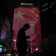 A man looks at his phone near a building in Beijing with a giant projected image of the Chinese national flag. 