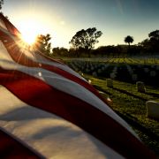 The sun sets over a U.S. flag at a veterans cemetery in Los Angeles, California, in May 2018.