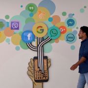 A mural of social media logos in a building in Bangalore. An Indian visitor walks past a mural of social media logos in Bangalore.