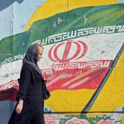 A pedestrian walks past a mural depicting the Iranian national flag in Tehran, Iran. 