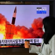 A woman walks past a screen showing footage of a North Korean missile test in Seoul, South Korea, on March 29, 2020. 