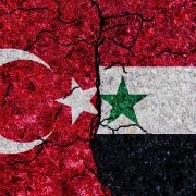 The Turkish and Syrian flags are split by a crack.