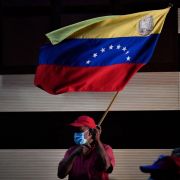 A supporter of the ruling United Socialist Party of Venezuela waves the flag of Venezuela on Jan. 10, 2022, in Barinas, Venezuela.