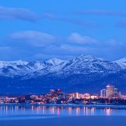 A skyline view of Anchorage, Alaska, and the Chugach Mountains at dusk.