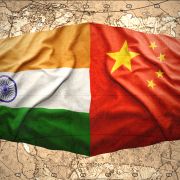 An image depicts waving Chinese and Indian flags overlaying a map of the world. An image depicts waving Chinese and Indian flags overlaying a map of the world.