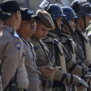 An Indonesian policeman (5th L) checks his mobile phone while standing in line during a security roll call in Banda Aceh on April 11, ahead of the country's general elections. 