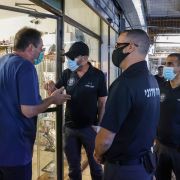 A store-owner wearing a mask speaks with officials at the Carmel Market in Israel's Mediterranean coastal city of Tel Aviv on Nov. 17, 2020.