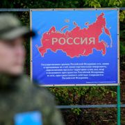A Russian soldier stands next to a poster showing a map of Russia during military drills in Siberia. 