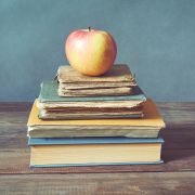 An apple sits atop a stack of books.