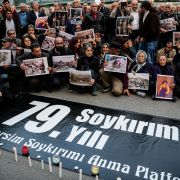 People hold pictures depicting victims of the Dersim operation in the 1930s, behind a placard marking the 79th anniversary of the genocide during a demonstration on May 4, 2016 in Istanbul. 