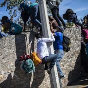Central American migrants, mostly from Honduras, climb over a barrier as they try to reach the U.S.-Mexico border on Nov. 25, 2018, near the El Chaparral border crossing in Tijuana, Baja California State, Mexico.